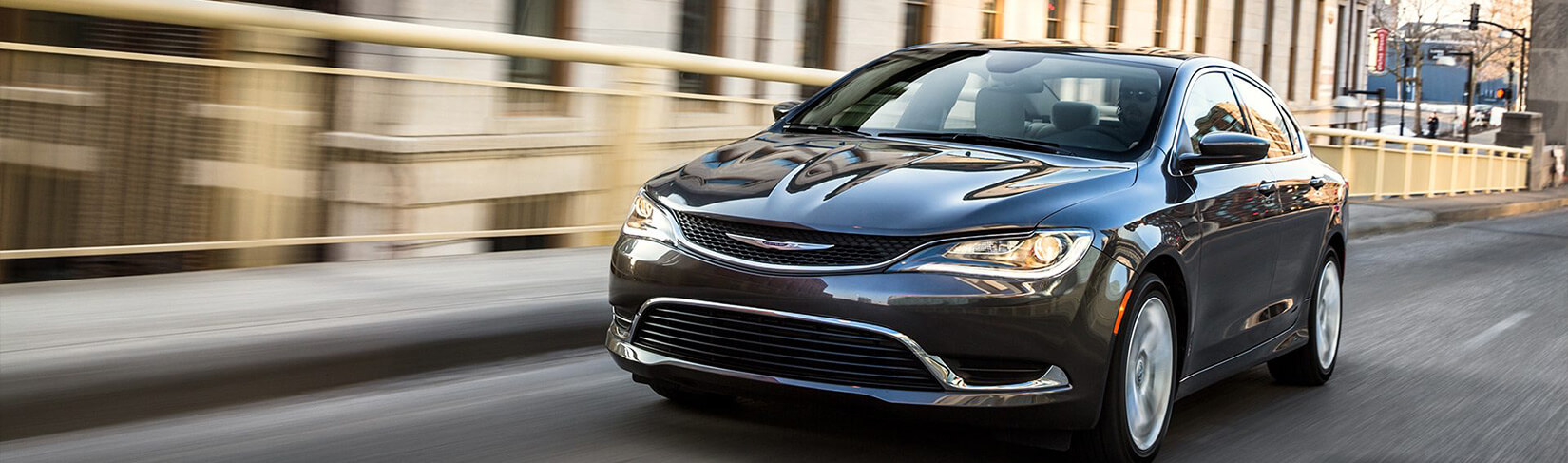 Dark blue Chrysler sedan driving over a bridge.